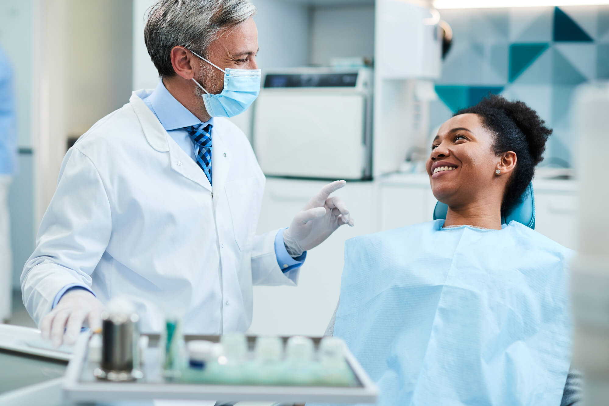 Happy dentist talking to black female patient during dental exam at dentist's office