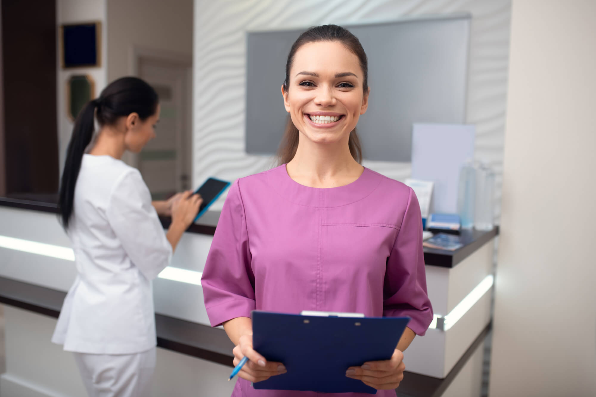 Smiling broadly. Beaming woman wearing uniform working in dental clinic smiling broadly