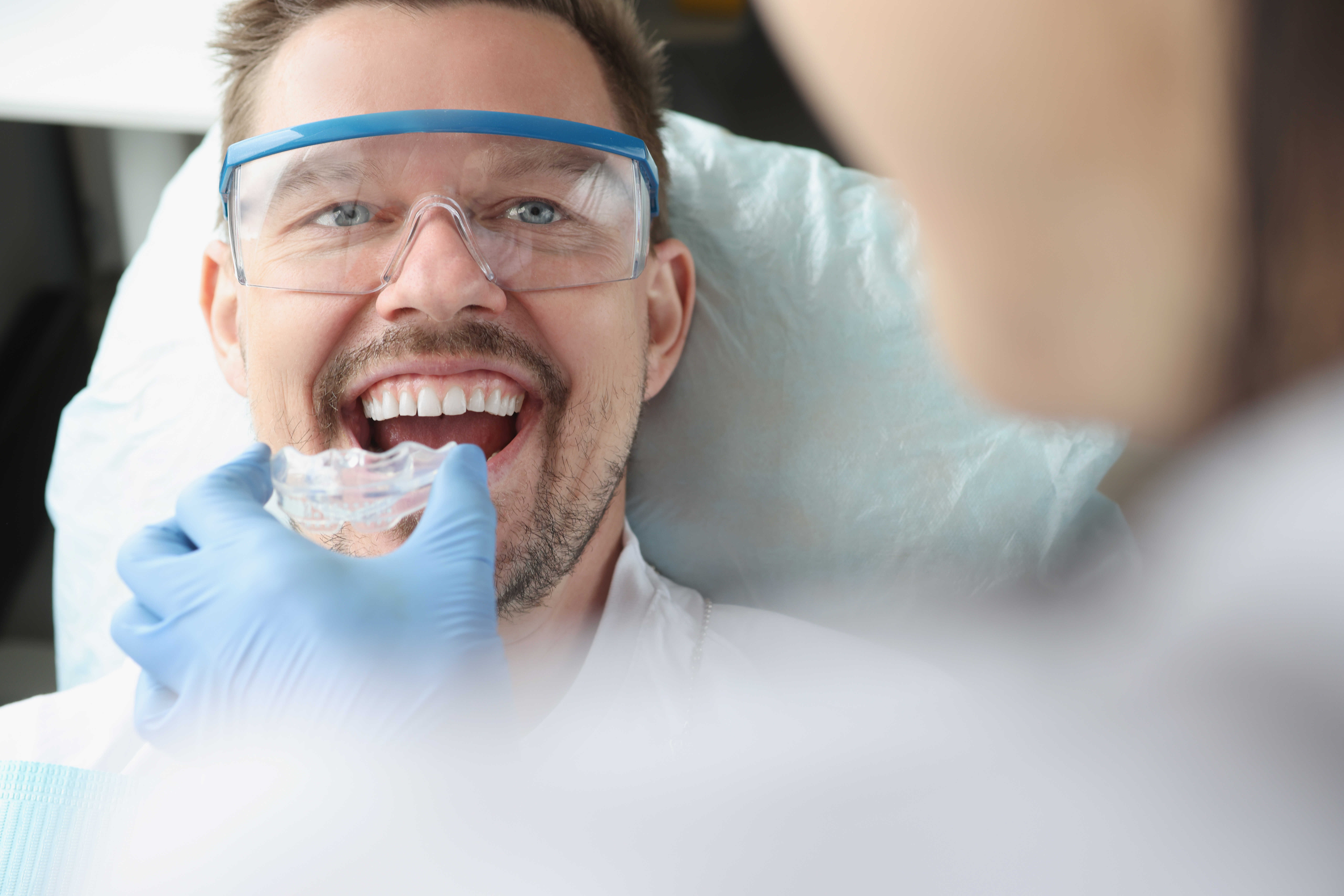 doctor-tries-on-plastic-mouthguard-for-young-smiling-man-to-correct-bite